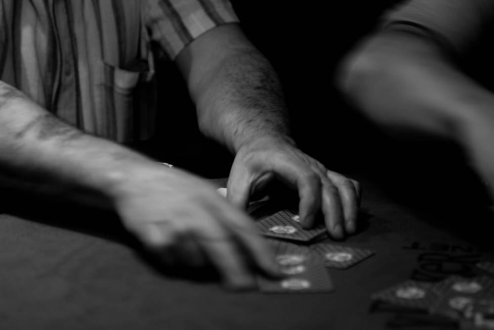 Tangan pemain menyusun kartu di atas meja poker