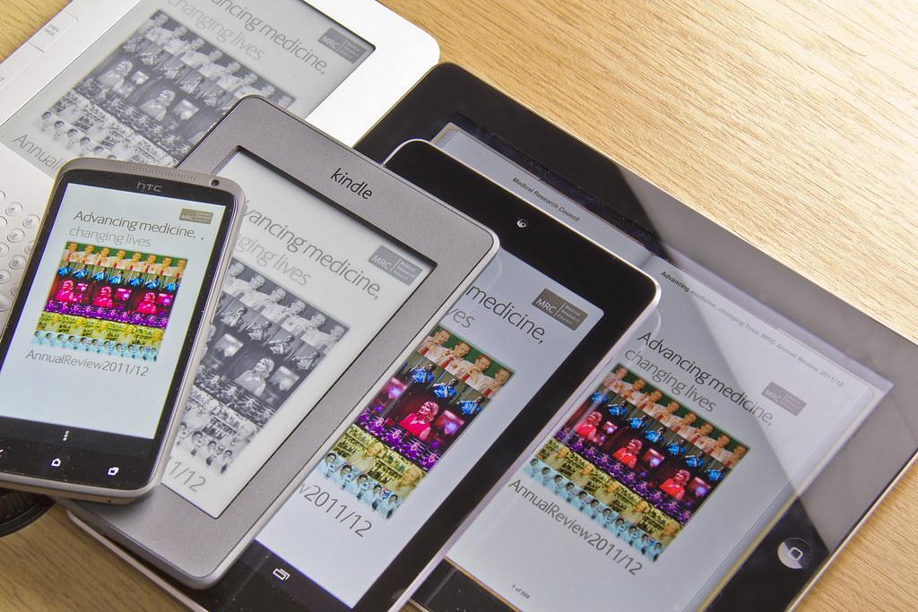 Seseorang membaca artikel di tablet sambil bersantai di sofa